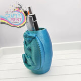 Teal 3d printed chameleon pen pot shaped like dinosaur with textured scales and coiled tail for colorful desk use