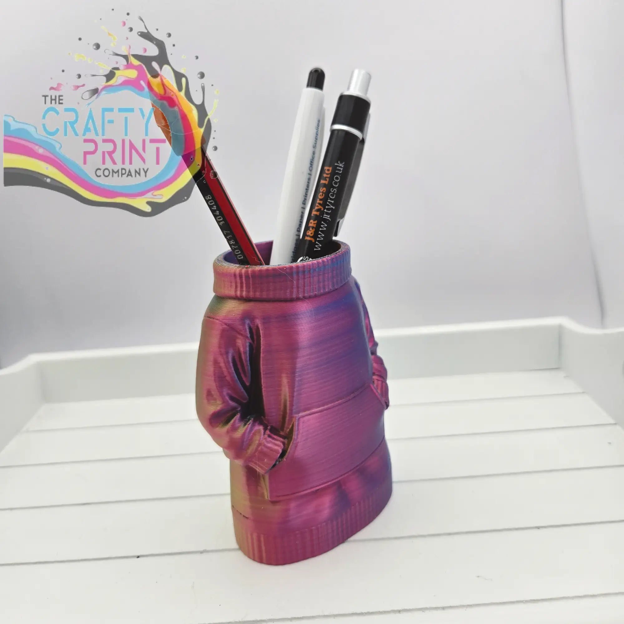 A vibrant iridescent purple and pink 3d printed jumper pen pot shaped like a sweater for desk organization
