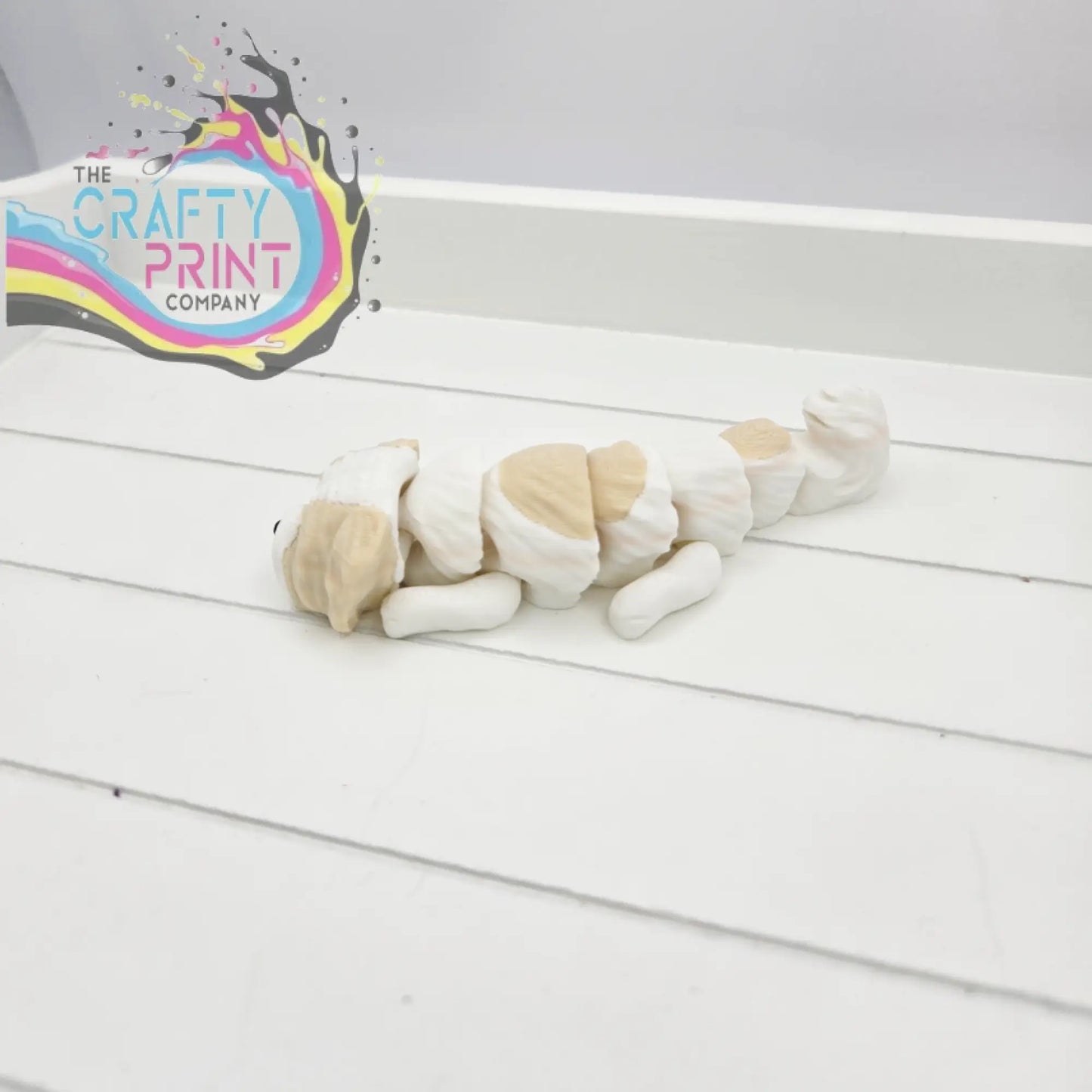 A charming white and beige ceramic shih tzu dog figurine sleeping in smooth rounded segments for keyring or fidget use