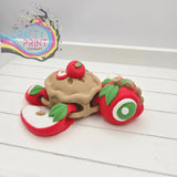 A whimsical 3d-printed red and beige sea turtle flexi fidget toy with green leaf accents inspired by apple pie