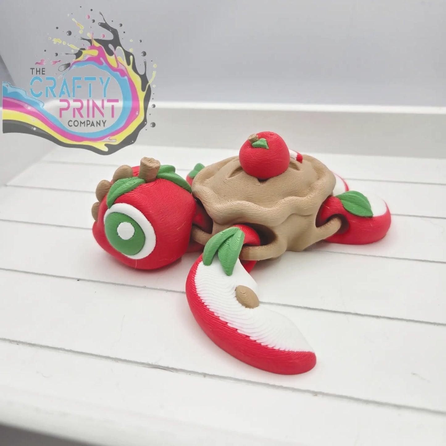 Whimsical red and beige apple pie sea turtle flexi fidget toy with green leaf accents and articulated design