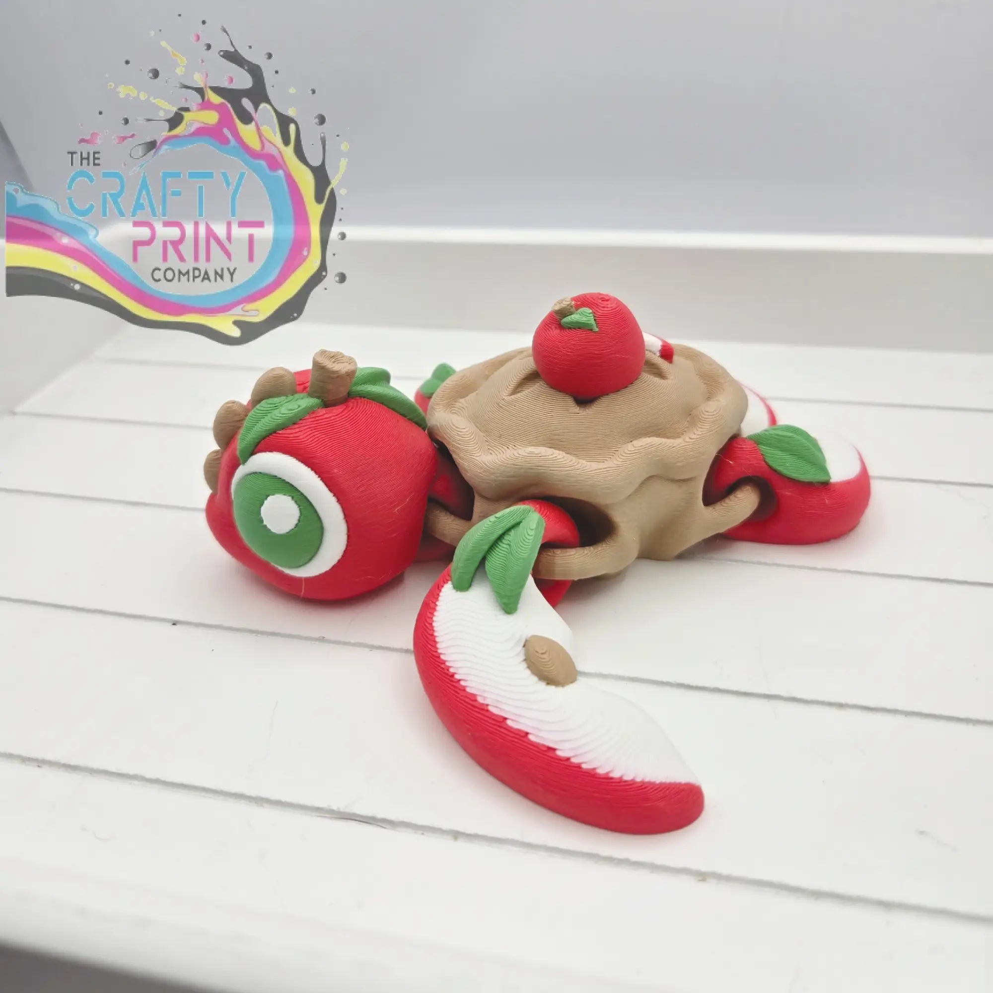 Whimsical red and beige apple pie sea turtle flexi fidget toy with green leaf accents and articulated design
