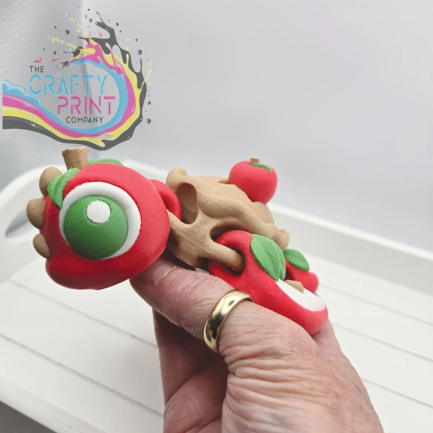 Apple pie sea turtle flexi fidget toy in red and beige clay with a green eye and articulated design