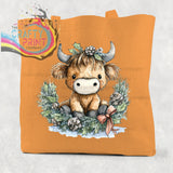 Orange cotton tote bag featuring a cute highland cow wreath with holly and pinecones in a festive design
