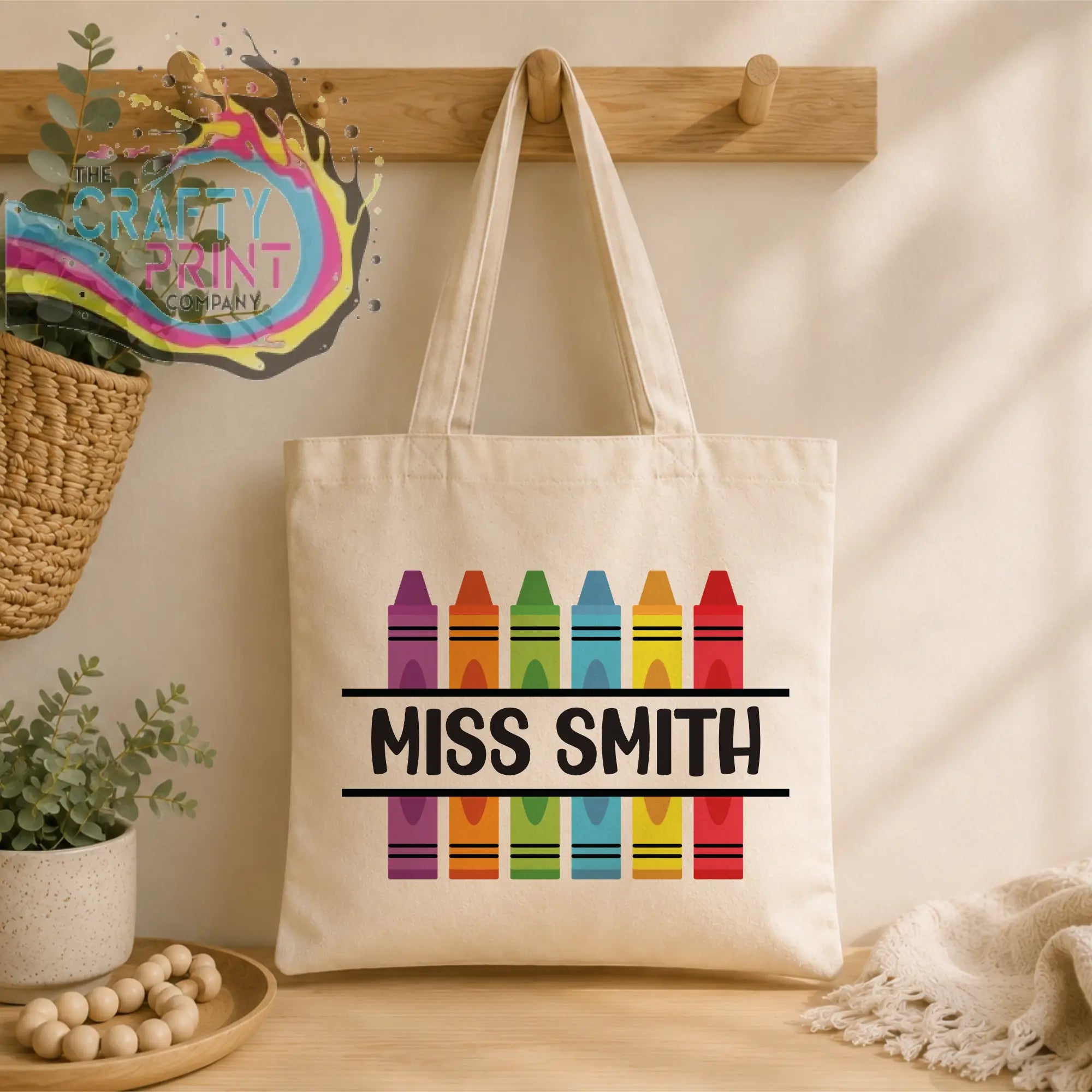 Cream-colored canvas personalised crayon teacher tote bag with colorful rainbow crayon design and miss smith text