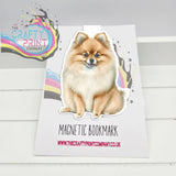 A charming fluffy pomeranian magnetic bookmark with colorful splatter accents on a white background