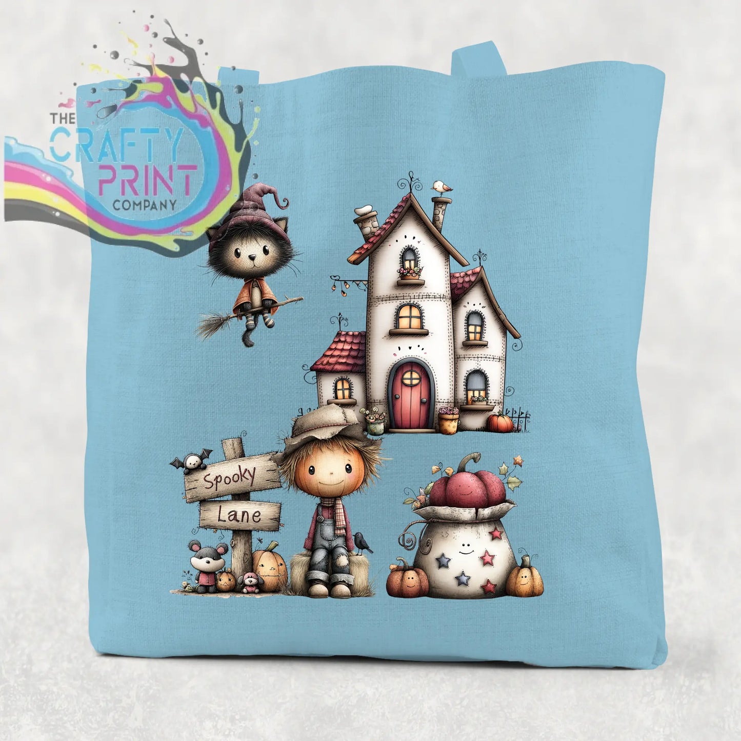 Light blue cotton re-usable tote bag with spooky lane halloween illustration of witch cat haunted house and scarecrow