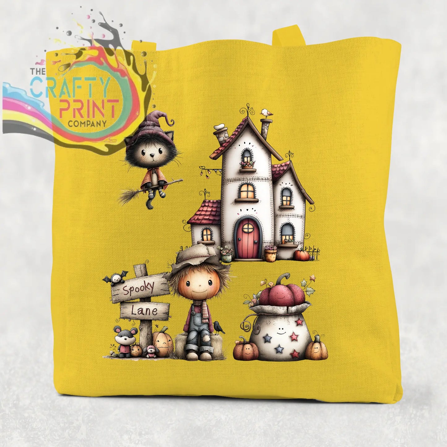 Yellow cotton re-usable tote bag featuring spooky lane halloween illustration with witch cat haunted house and scarecrow