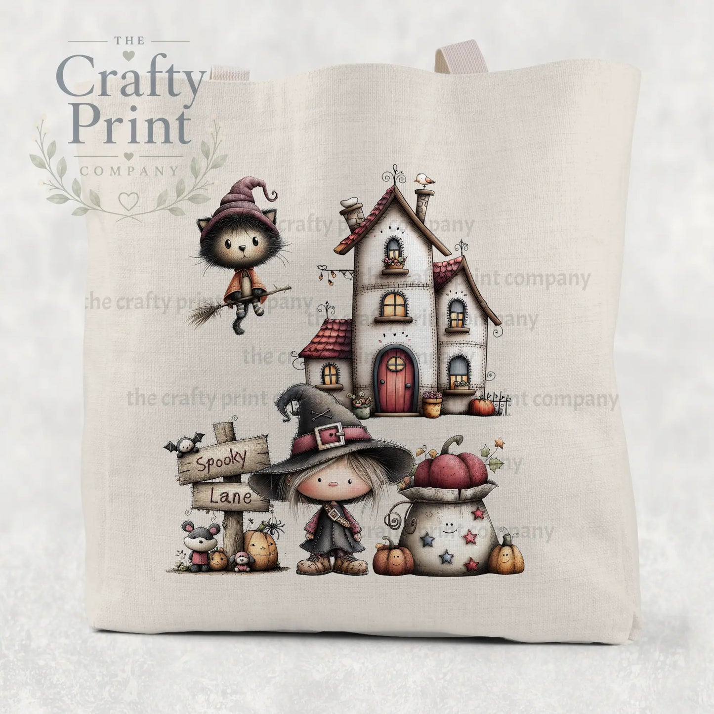 Beige cotton re-usable tote bag featuring spooky lane halloween witch illustration with cat on broomstick and cozy cottage