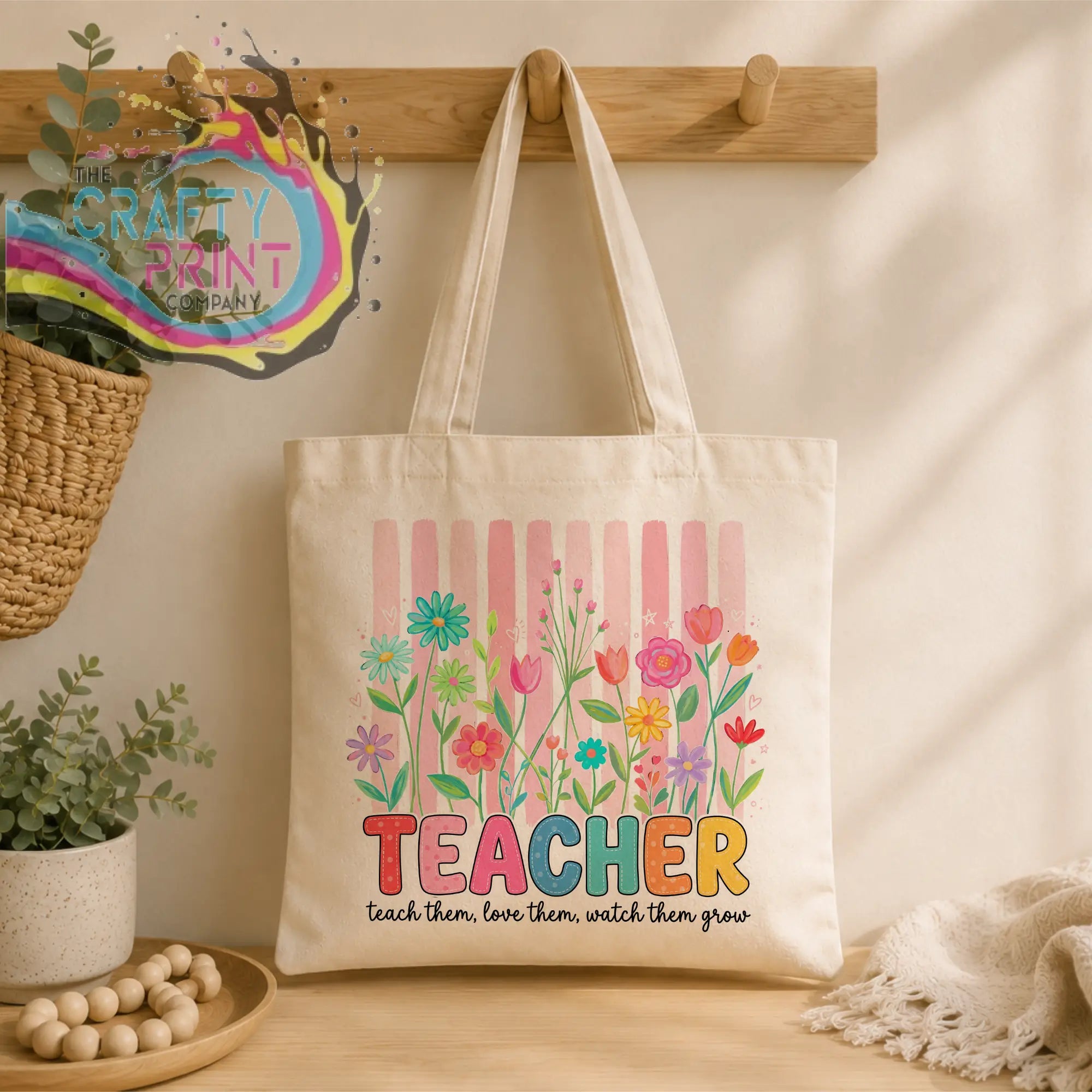 Cream-colored canvas re-usable tote bag with vibrant floral design and colorful teacher text teach them love them watch them grow